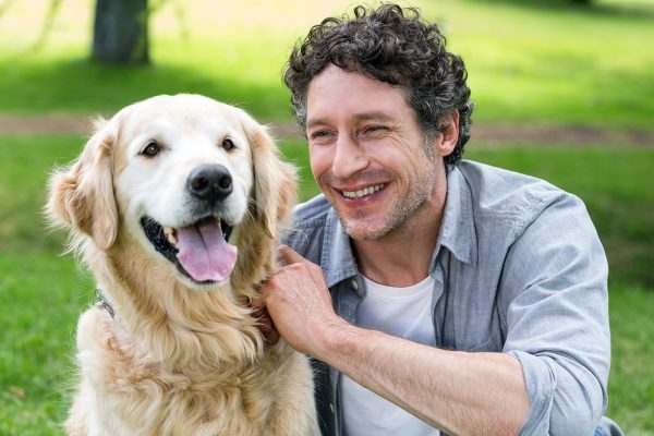 smiling-man-with-his-dog-in-park-on-a-sunny-day-PDNWL2X.jpg